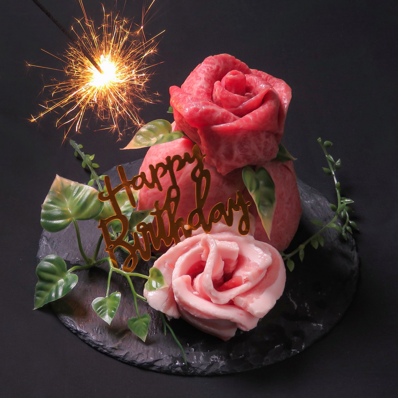 バラのように盛りつけたお肉に、花火とHappy Birthdayの飾りを添えた肉ケーキ